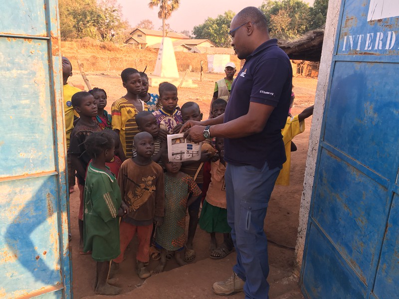 Sylvain Tiako shows a diagram on paper to a group of children
