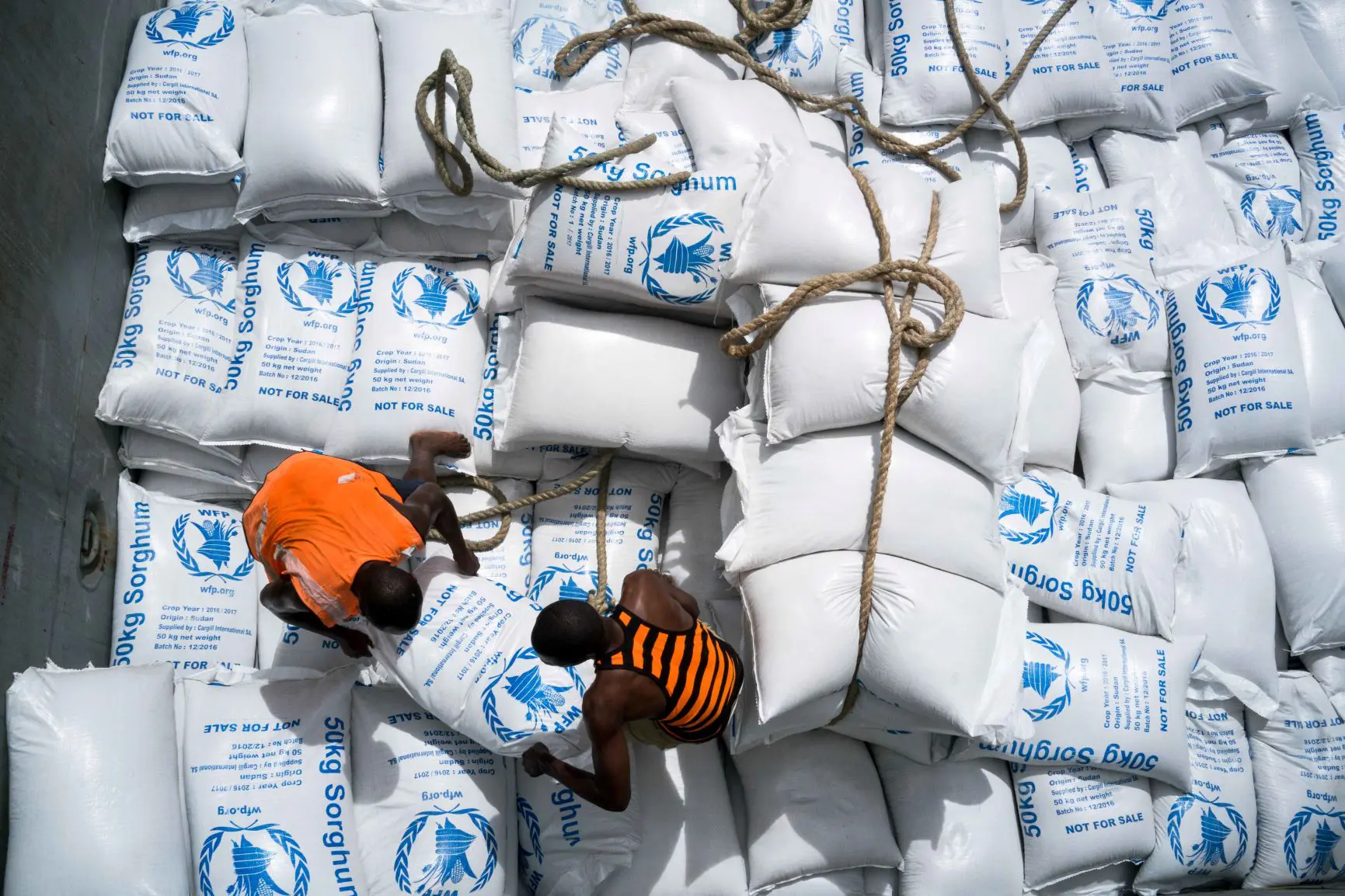 Porters loading WFP food bags onto cargo ship.