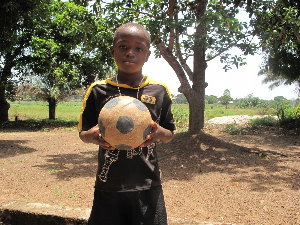 Osman stands with his soccer ball in his hands at the Kambui Center in Sierra Leone