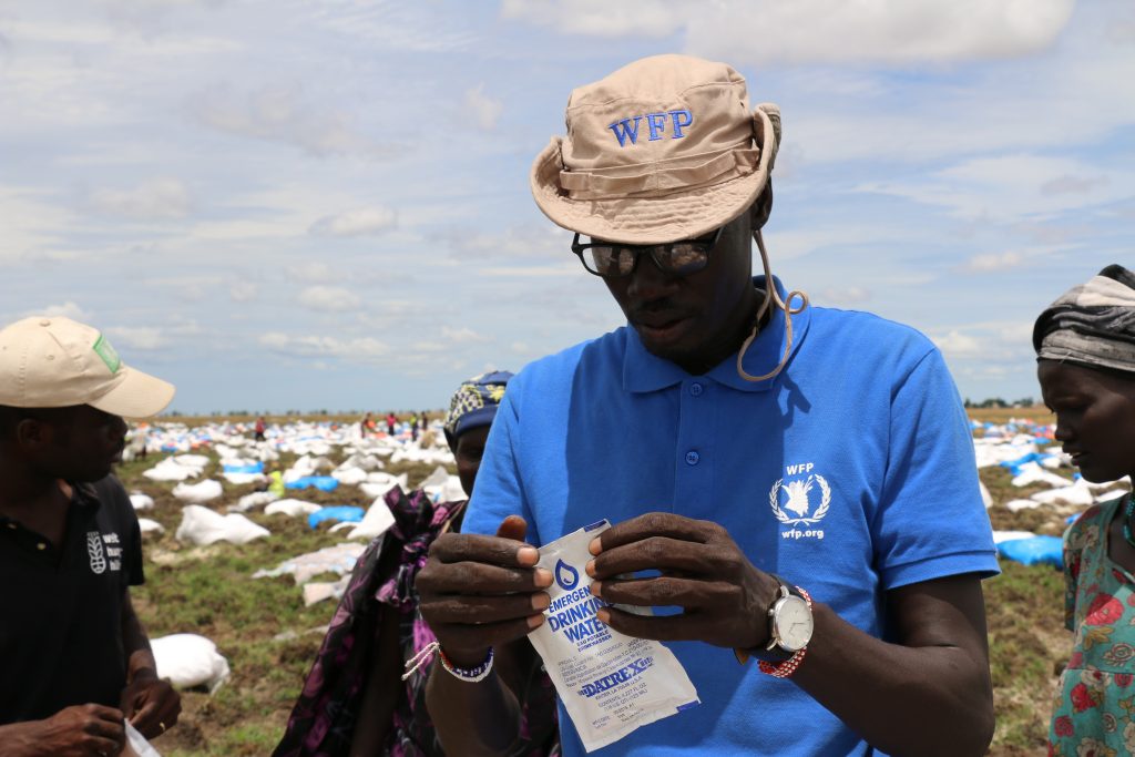WFP drop zone coordinator, Kang Koriyom, opens a packet of drinking water after an airdrop in Ganyiel, Unity State.