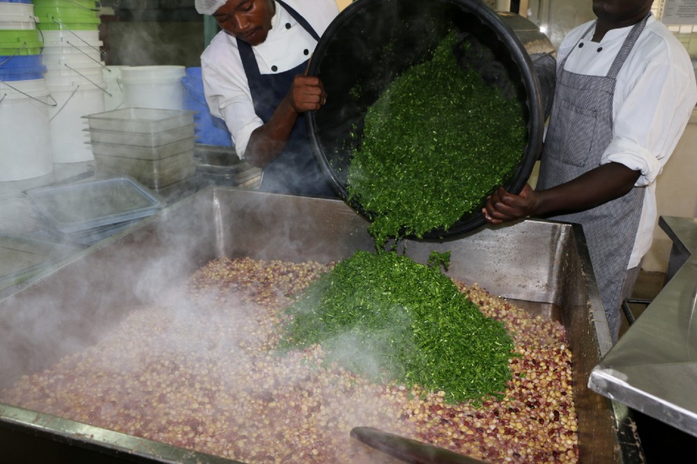 Cooks at the Little Bells Primary School in Kenya prepare a nourishing meal for the students using locally grown green beans that had been rejected for export for cosmetic reasons.