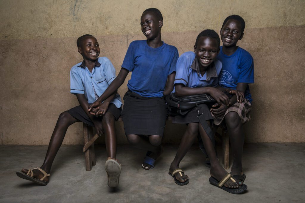 Four girls in blue shirts laugh while seated, posing for a photo.