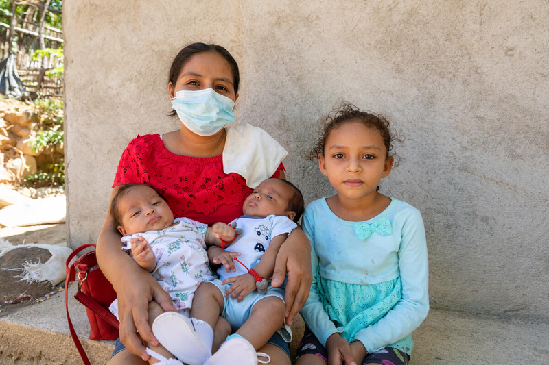 mother sits with young daughter and two babies