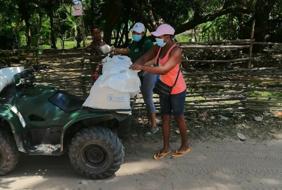 3 people in masks load a 4 wheeler with bags of food.