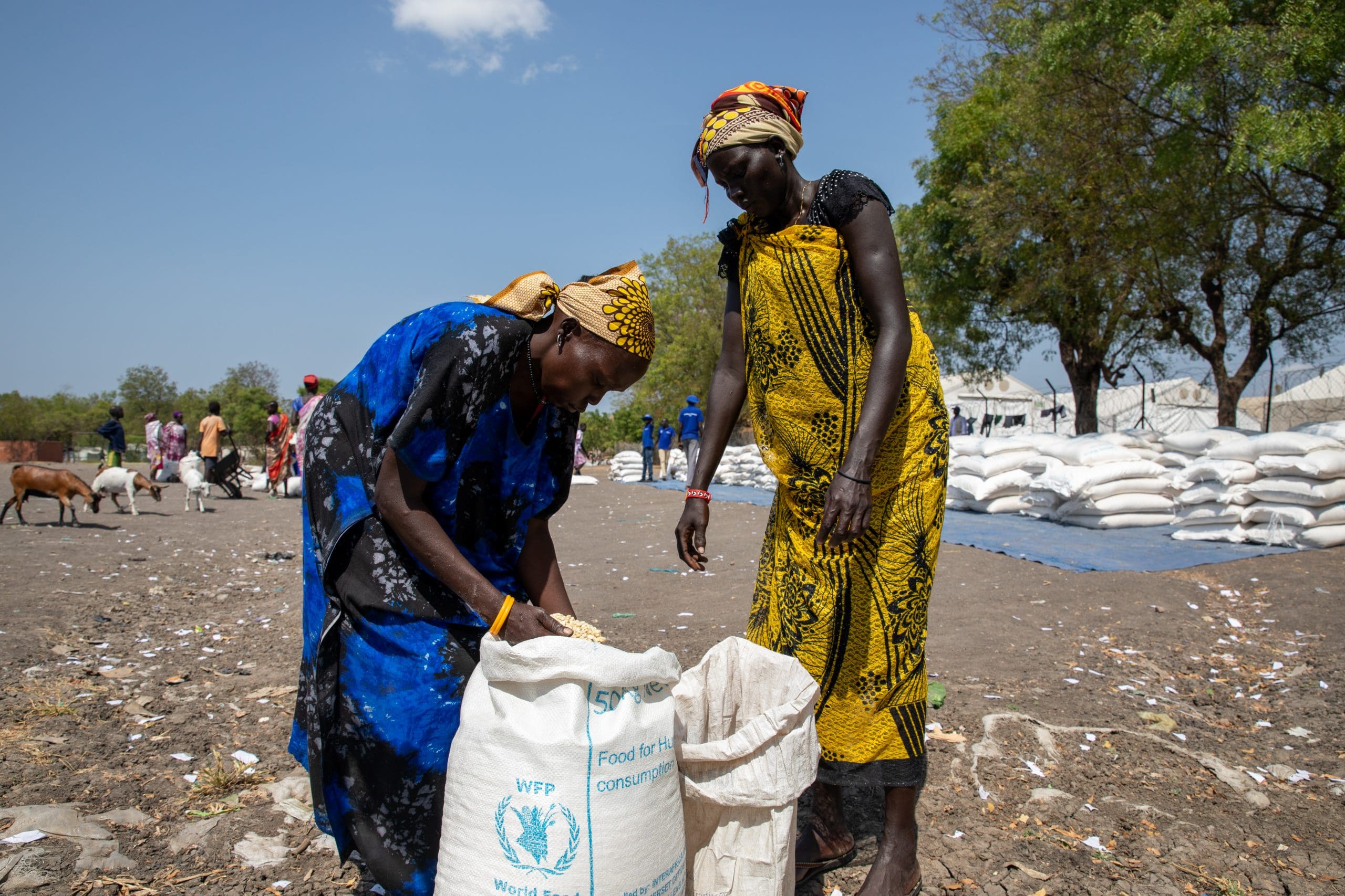 two women bend over WFP bags of food