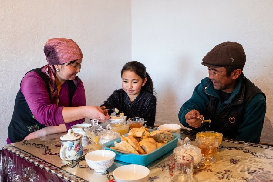 family gathers around table of food