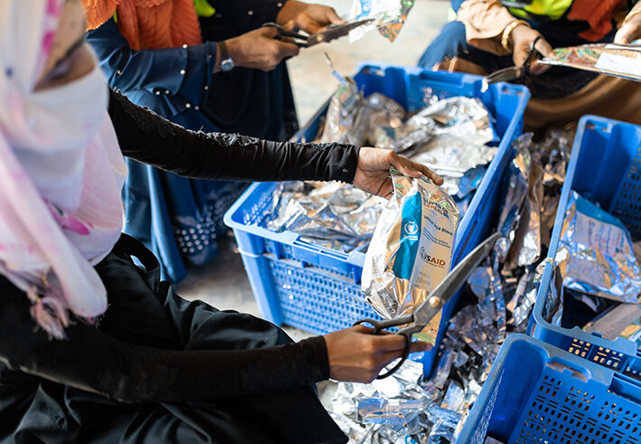 Rohingya woman sorts through UN WFP packaging in Cox's Bazar refugee camp in Bangladesh