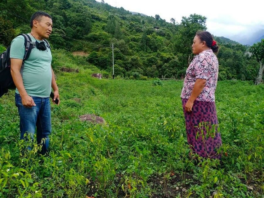 woman in purple shirt stands in field and talks to man