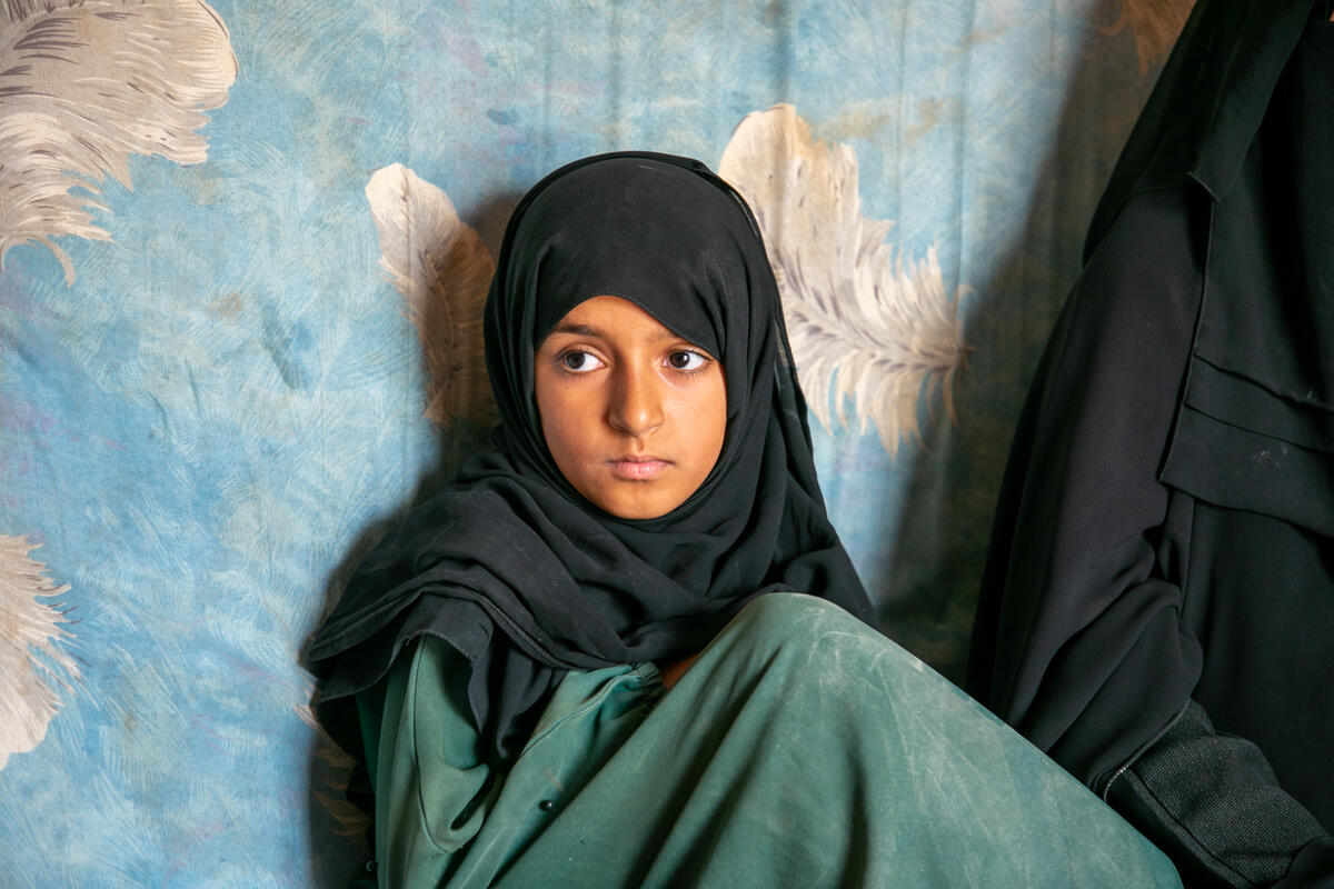 young girl in black headscarf and green dress