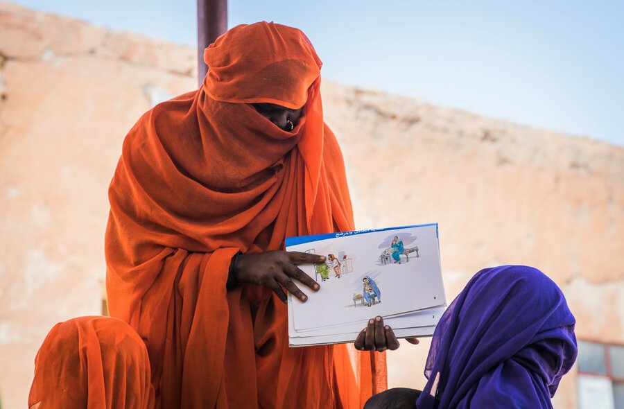 woman in orange headscarf and dress teaches about health