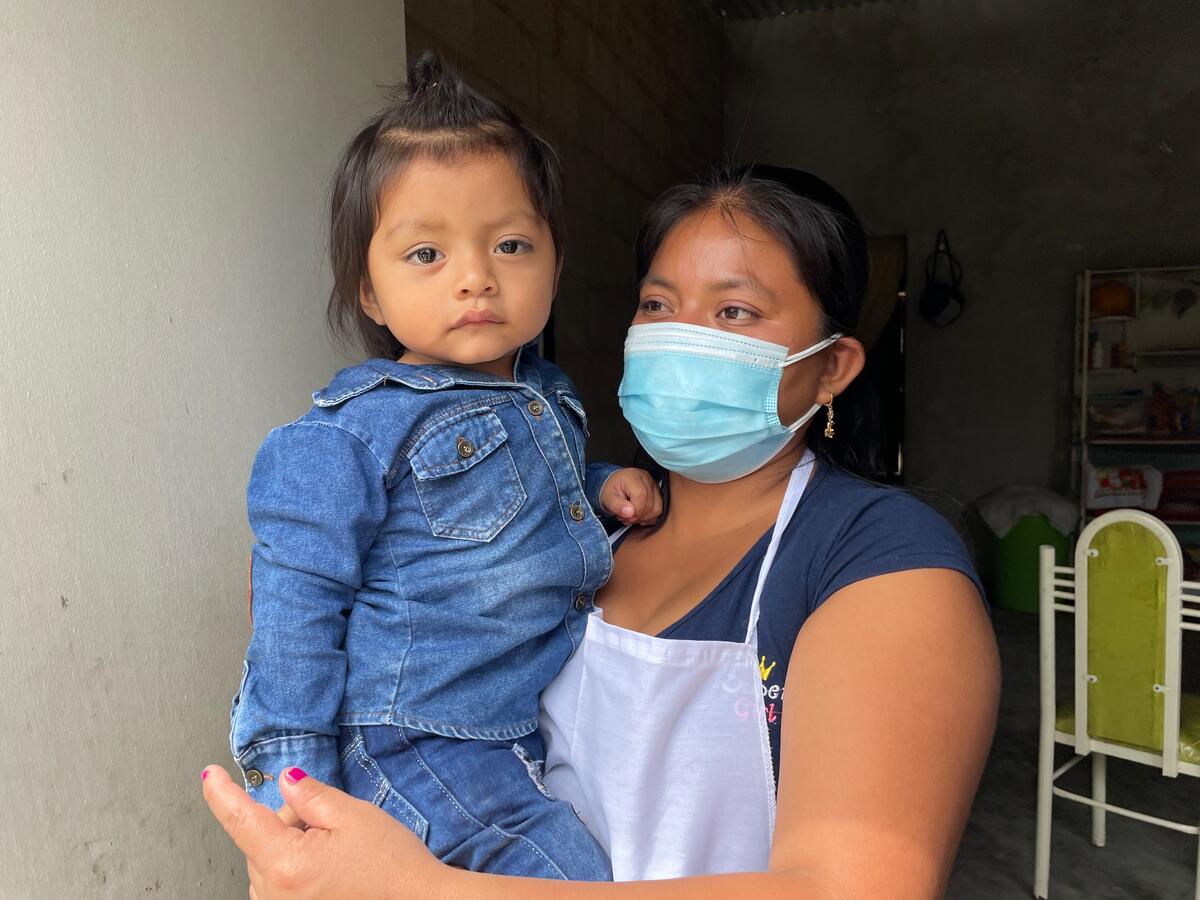 mother in COVID-19 health mask holding young daughter