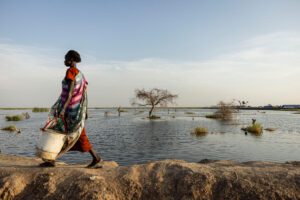 A woman walks past flooded waters in South Sudan