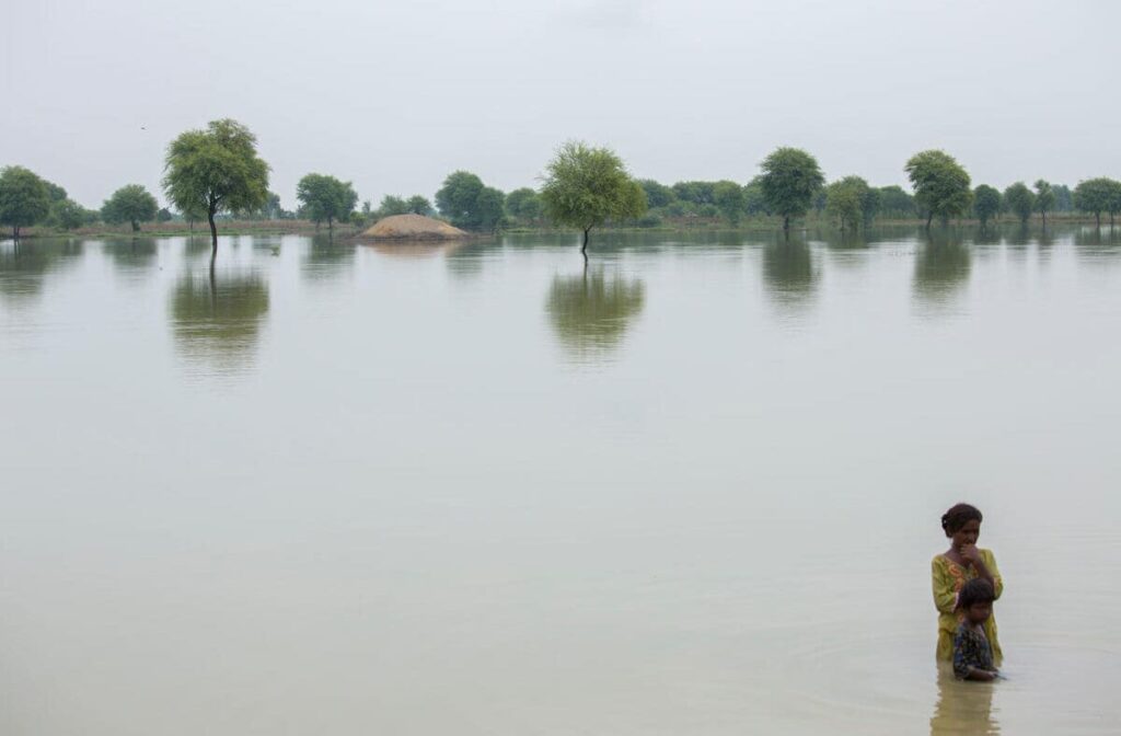 a woman stands with her child in flooded land