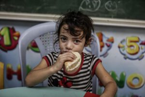 A young girl takes a bite of bread