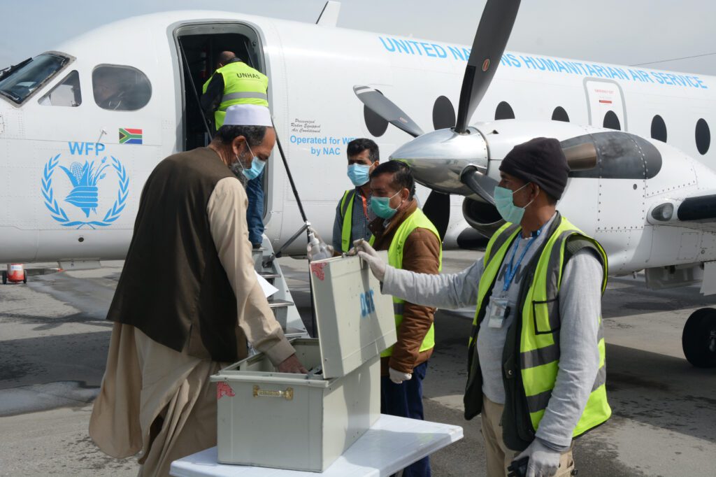 Staff members stand in front of an airplane wearing masks.