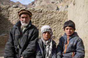 father and two sons sit outside family home