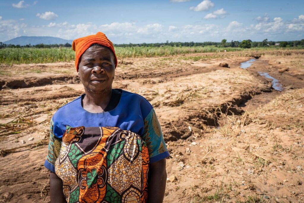 Woman stands in field hit by tropical cyclone
