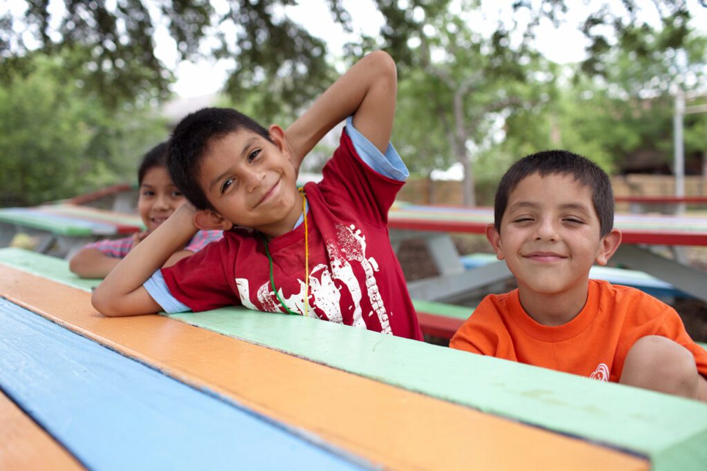 Three kids smile and look at the camera.