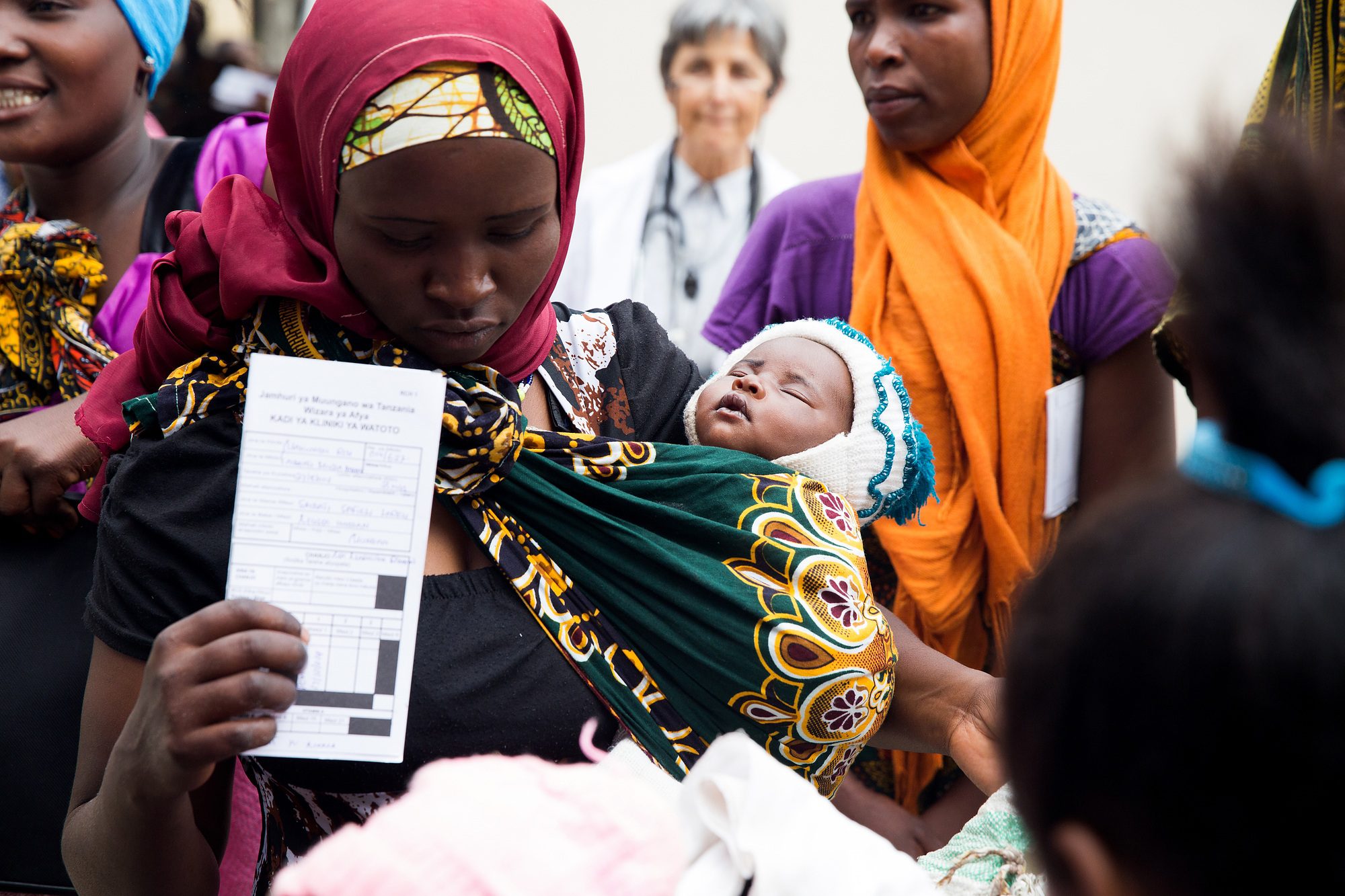 A woman holds her newborn baby and her monthly ration card