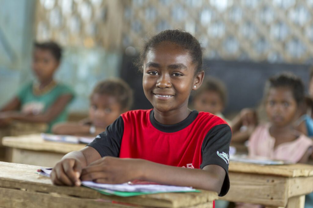 a young schoolgirl sits at her desk in the