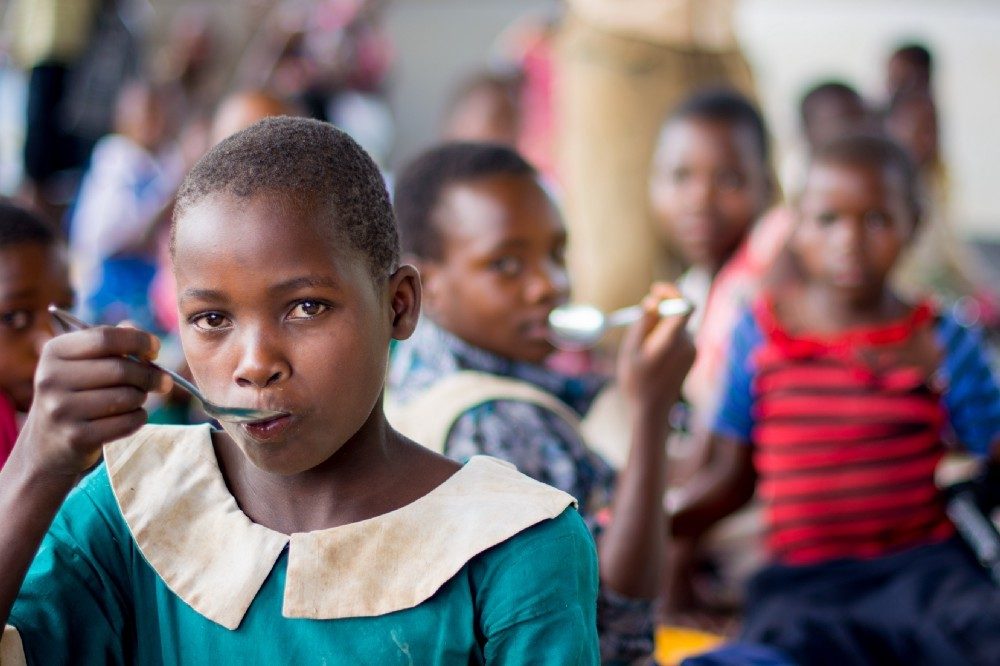 A young girl eats a spoonful of food.