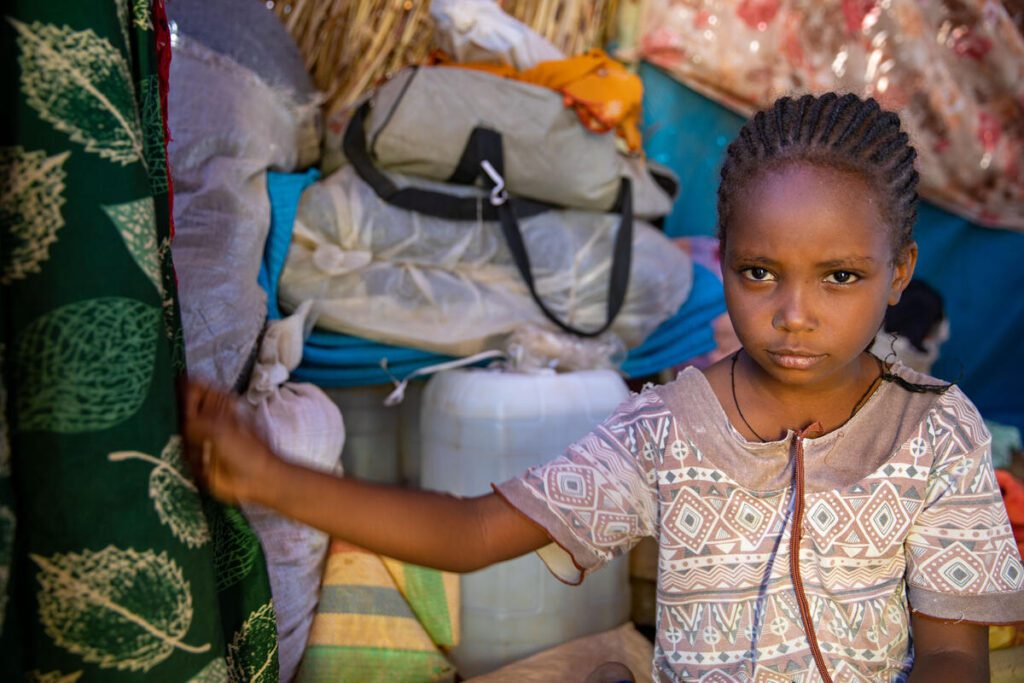 little girl standing in front of bags in home