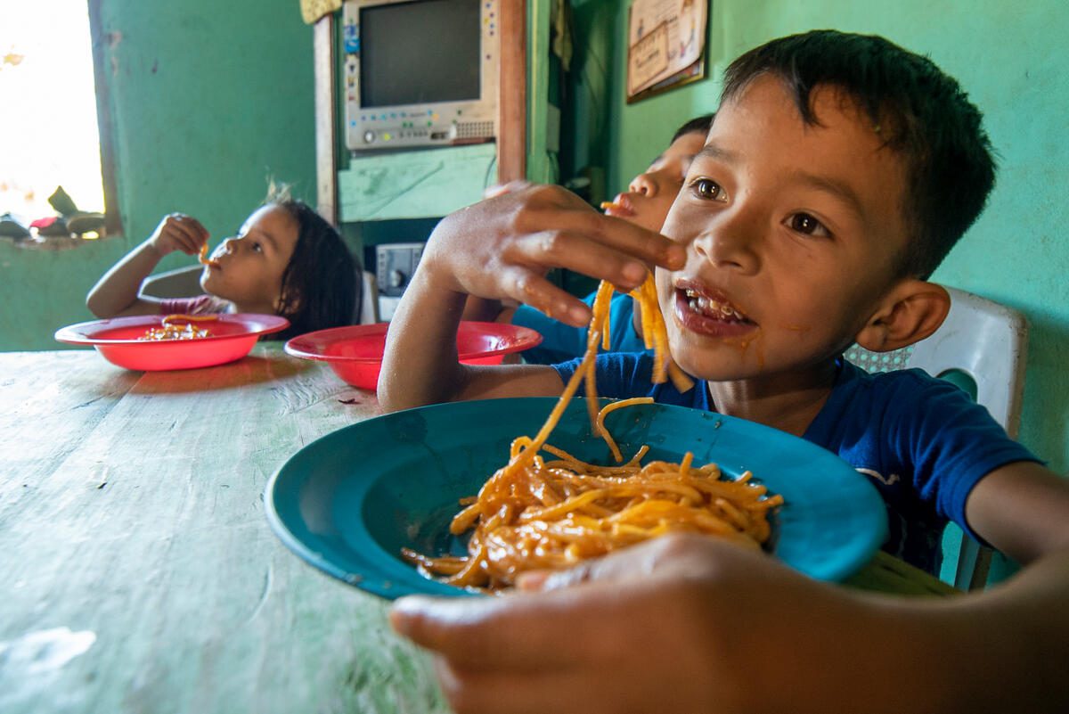 Honduras, Gracias a Dios neighborhood, Santa Bárbara Department, 11 February 2021

In the Photo (from left to right): Génesis, José and Jordin eating the meal prepared by her mother Marlene Rosales.

Marlene Rosales and her four children (Cinthia, Jordin, José and Génesis) are among the millions of Honduran affected by the socioeconomic impact of the COVID-19 pandemic and two hurricanes

Photo: WFP/Gerardo Aguilar

Marlene&#039;s husband used to earn US$10 per day by working on the construction business, but he lost his job due to the COVID-19 lockdowns. For a while, her husband found a job in a woman‘s house, but that house was destroyed by the hurricanes. 
After the family was forced to return to Honduras, they have been making a living out of selling scrap metal. They make US$0.08 for every 2 pounds of scrap metal. 

”It&#039;s nothing, but at least it&#039;s enough for a bag of coffee and sugar,” said Marlene.

The socio economic crisis caused by the COVID-19 pandemic and 2 hurricanes in late 2020 have severely affected the food security of millions of Hondurans. Hurricanes Eta and Iota affected some 4.5 million people and left damages estimated in US$1.9 billion, according to an assessment carried out by the Economic Commission for Latin America and the Caribbean (ECLAC).