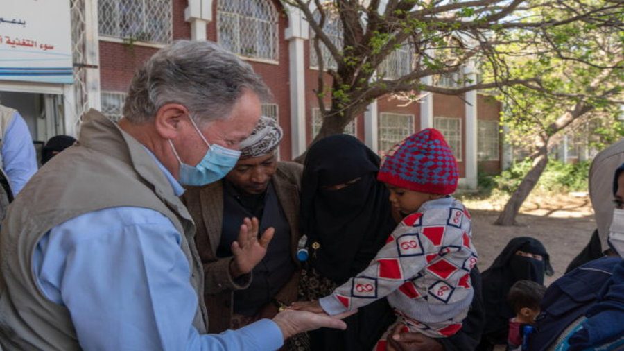 WFP Executive Director David Beasley speaks to mother in headscarf and child in Yemen