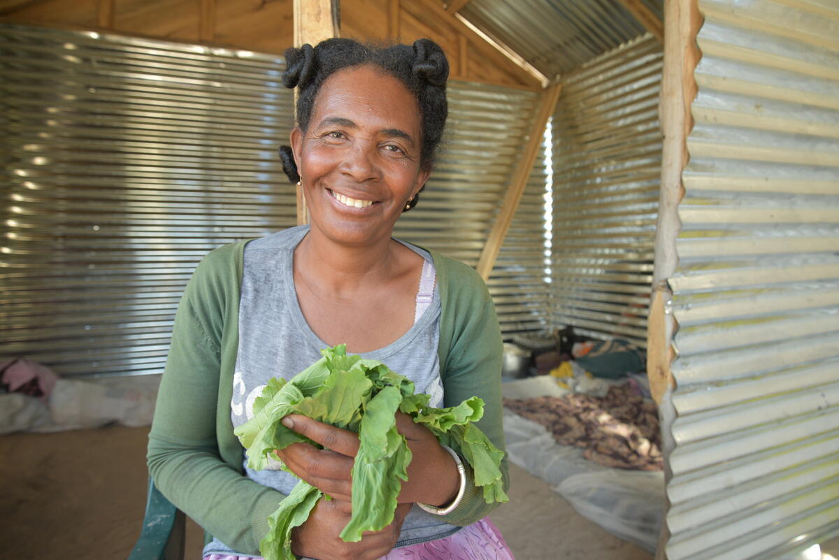 woman holding green vegetable and smiling