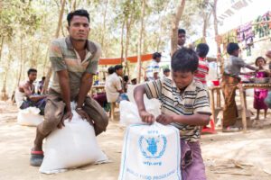 man and boy sit with WFP bags of food
