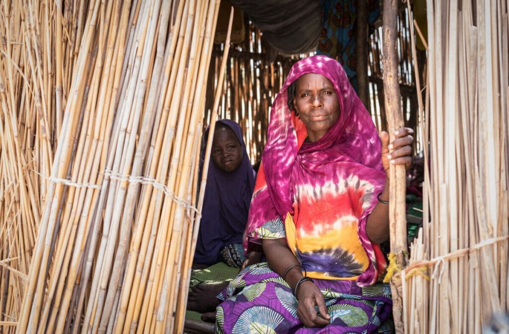 woman in red and orange shirt sitting in wooden home
