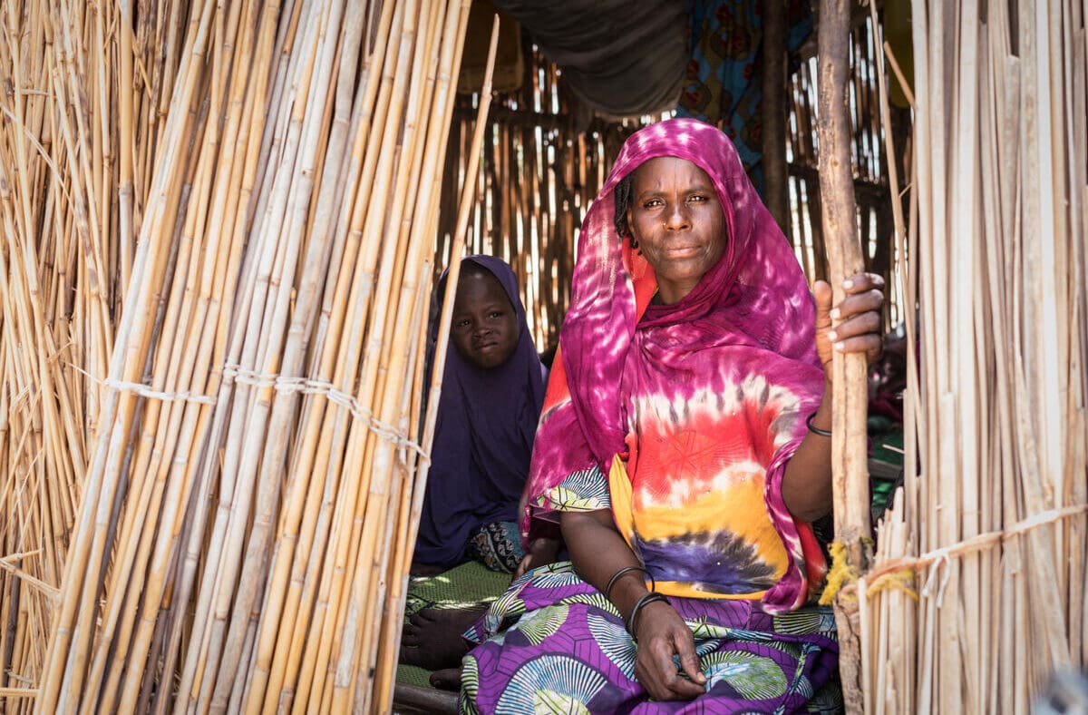 woman in red and orange shirt sitting in wooden home