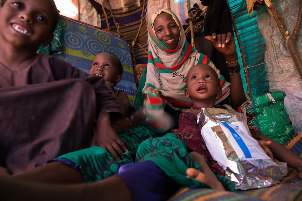 In this photo Mido poses with three of her children (From left to right - Mariam, aged 7, Shamsa, aged 4, and 12 month old Fatun) inside the small shelter they now call home in an IDP camp in Kabasa, Dolow. Also pictured is a bag of super cereal which is part of the nutritional supplementation the receive from WFP.

After a forth consecutive year of drought and increasing security concerns the family left the settlement where they lived and made their way to Dolow. It was a brutal month-long journey - barefoot and only with the clothing they wore. Along the way Mido lost one of her five children to hunger and he was buried enroute. 

Mido said, “We left our home because we had nothing left – we just had drought and hunger.” 

The family now live in a small dome-shaped shelter made from a patchwork of fabrics and plastics in the Kabasa IDP camp. Mido shares cooking utensils with her mother and siblings who have a larger shelter next door to theirs. 

The shelter is in a new extension to the camp, that has developed with the influx of new arrivals fleeing the drought.

Mido’s youngest daughter Fatun suffers from moderate acute malnutrition and they have been referred to the health clinic to receive WFP funded nutrition supplements (plumpy’sup and super cereal) to keep malnutrition at bay