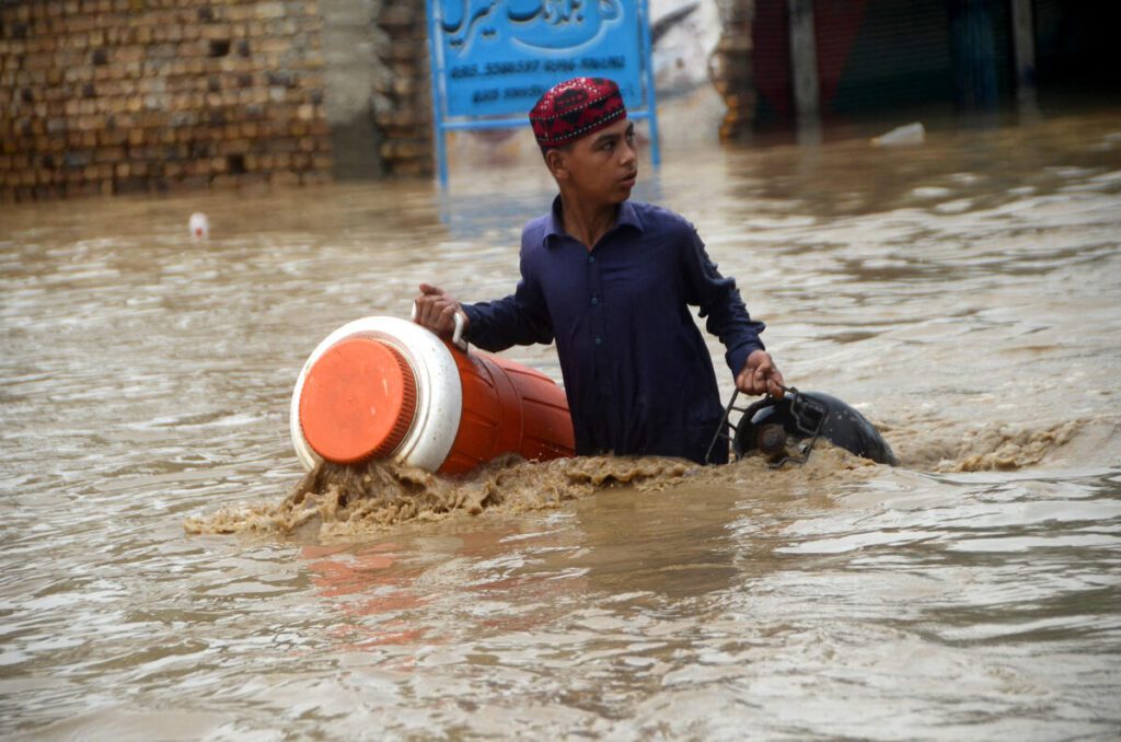 A young boy wades through a flooded area in Peshawar, Khyber Pakhtunkhwa