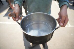In Gaza, child holds saucepan filled with little water
