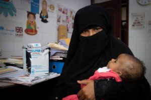 a mother in a burka cradles her malnourished baby