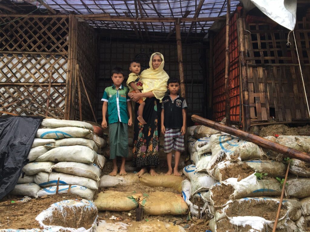 a woman stands outside her home with her family
