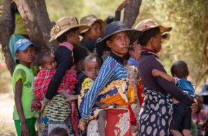 mother holding child on her back in crowd of people
