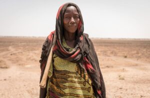woman in brown and pink headscarf standing in desert field