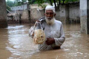 Man wades through flooded waters holding bread