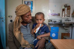 a father holds his malnourished son