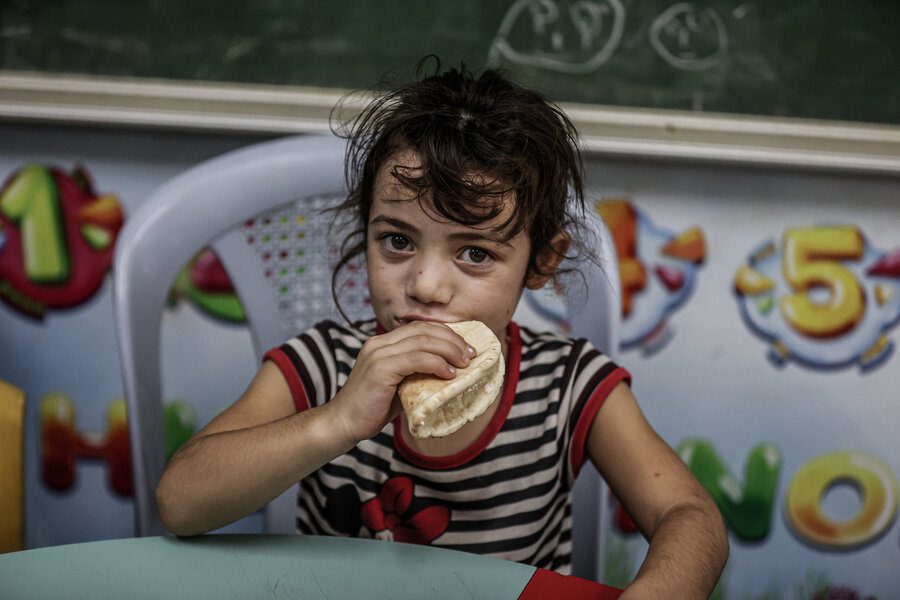 A young girl eats bread distributed by WFP, at a school shelter in Gaza.