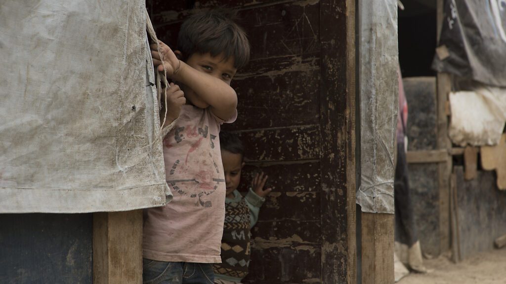 two small children peek out from their house