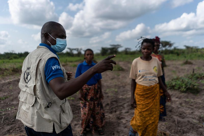 man in health mask speaks to group of farmers