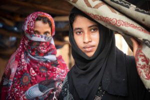 Two women in headwraps face the camera.