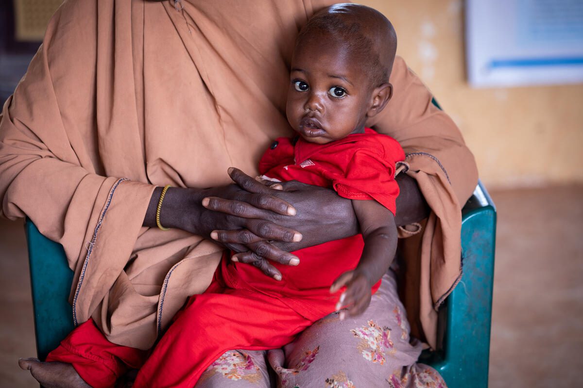 Somalia. Baby Abdi (12 months) is held by his mother Ambiyo (24) as they are seen to at the WFP funded MAM clinic at the Kabasa IDP camp in Dolow